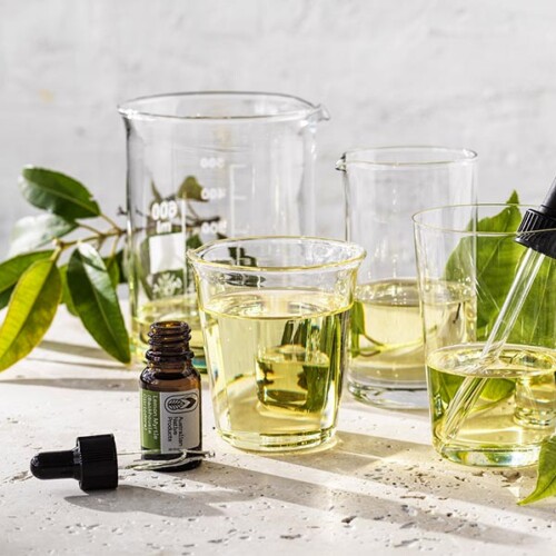 Lemon Myrtle 100% Essential Oil in dropper bottle beside measuring beakers and leaves ,USDA Organic certified